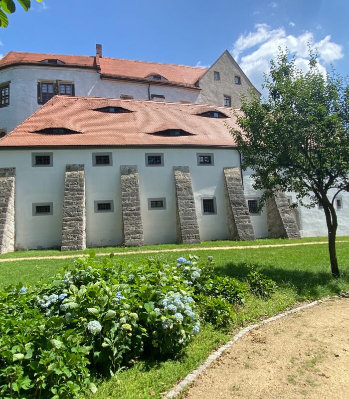 Blick auf das Schloss mit Vorburg und Stützpfeiler vom Rundweg im Garten