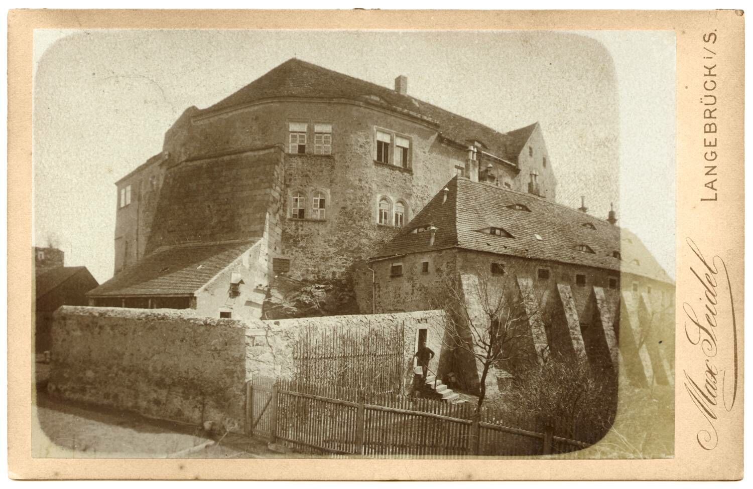 Foto in Vergrößerungsansicht öffnen: Schwarz-weiß-Foto um 1900 mit Hauptburg. Im Vordergrund die Mauern des Gefängnishofes und die Vorburg mit Stützmauern. Am rechten Bildrand Aufdruck nach oben "Max Seidel".
