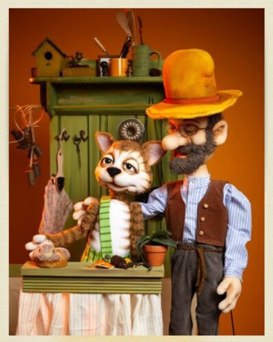 Puppenspiel-Szene aus Pettersson und Findus: eine Katze in einer grün-gestreiften Hose und ein Mann mit Bart und gelbem Hut stehen an einem grünen Tisch