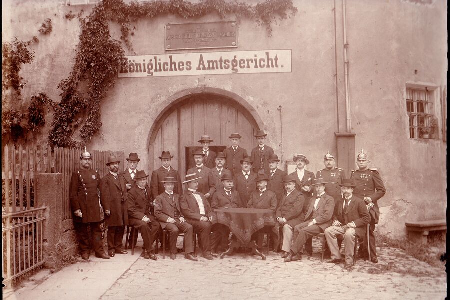 historische Schwarz-Weiß-Fotografie mit 22 Mitarbeitern des Königlichen Amtsgerichts vor dem stadtseitigen Tor 1908