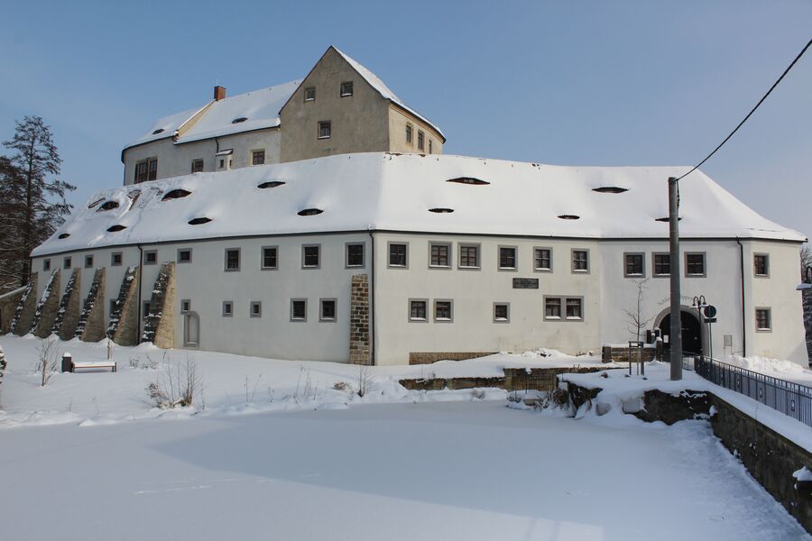 Farbfoto mit zugefrorenem Schlossteich und Blick auf die verschneite Vorburg