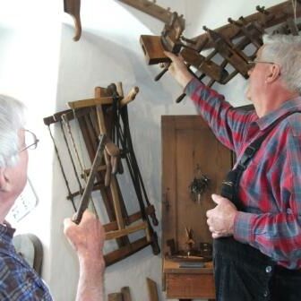 Zwei Männer, die Gebrüder Paulick, beim Anordnen von Werkzeugen und anderen Gegenständen in der Historischen Böttcherei.