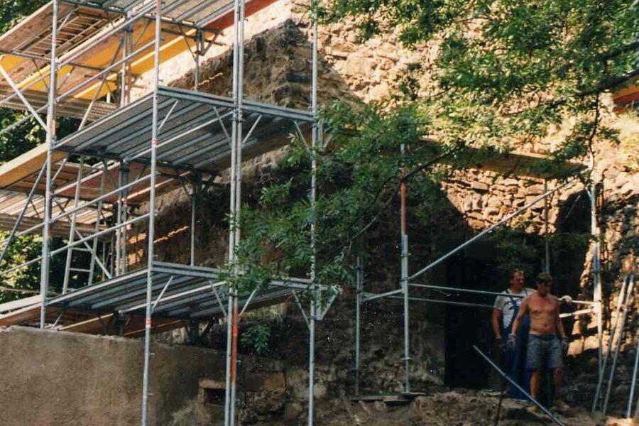 Baugerüst und Steine am Eulenturm, rechts stehen zwei Bauarbeiter am Gerüst.
