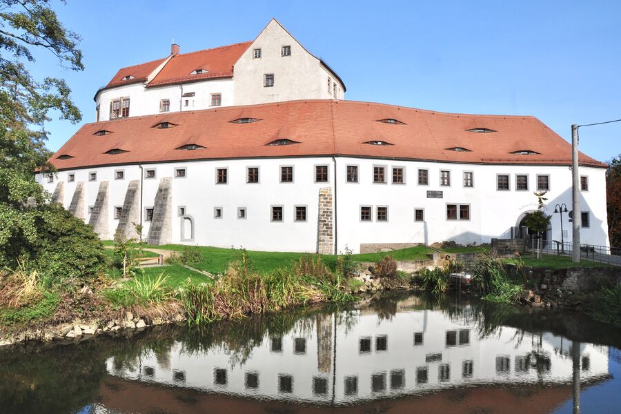 Farbfoto 2020 im Herbst mit Blick über den Schlossteich zur Vorburg mit der durchfensterten weißen Fassade und dem roten Ziegeldach