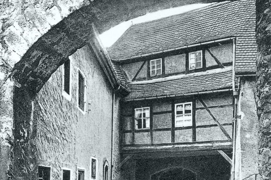 Historisches Schwarz-Weiß-Foto im unteren Schlosshof mit Blick durch den Strebebogen auf das Stadttor, das Amtshaus und die Zugangstreppe rechts.