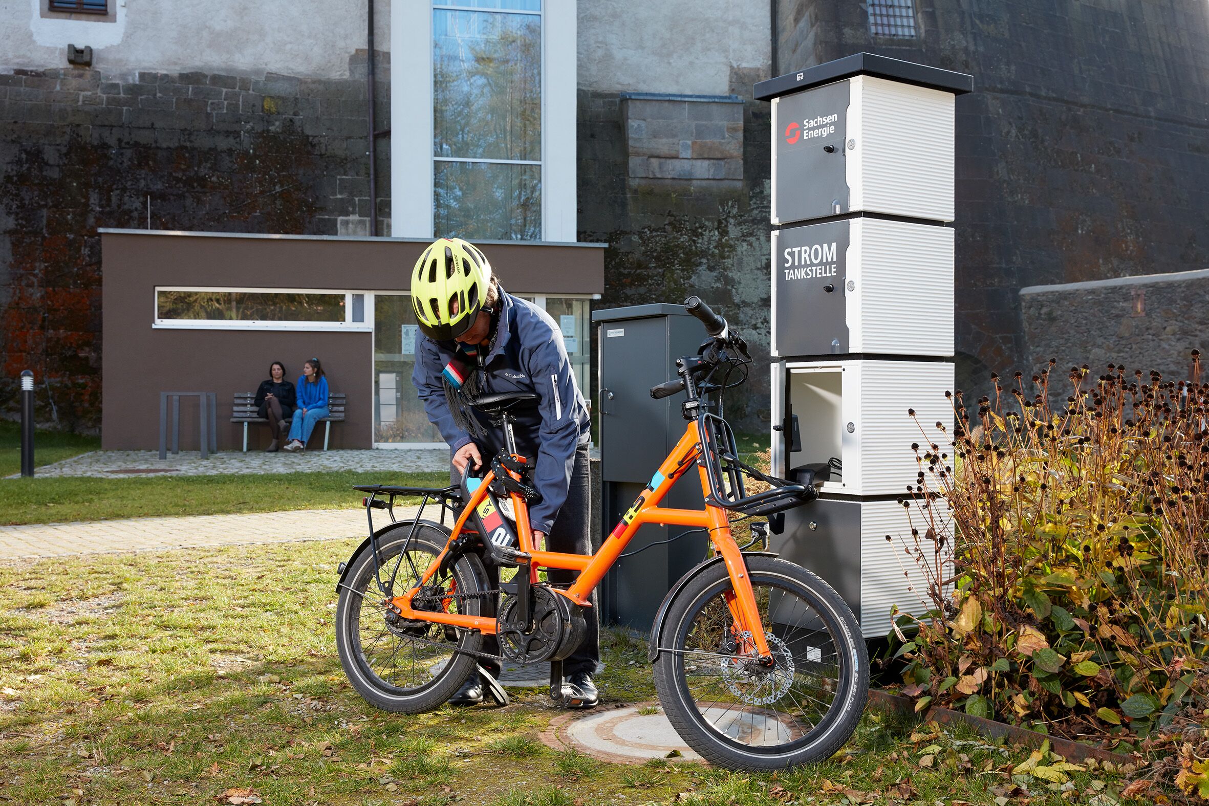 Eine Fahrradfahrerin nutzt die E-Bike-Ladestation im Schlossgarten