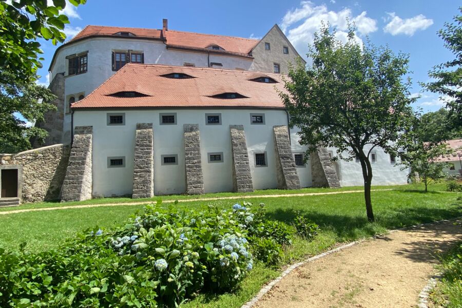 Blick auf das Schloss mit Vorburg und Stützpfeiler vom Rundweg im Garten