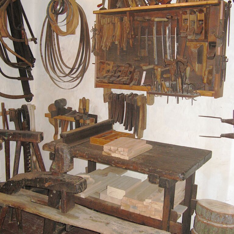 Arbeitsbank aus Holz, darüber befinden sich in einem Wandboard verschiedene Werkzeuge.