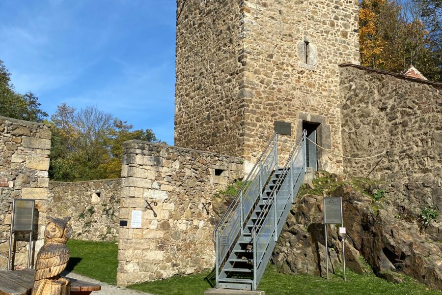 Eulenturm mit Metall-Treppe und links eine Sitzgruppe und eine Eulenstatue aus Holz