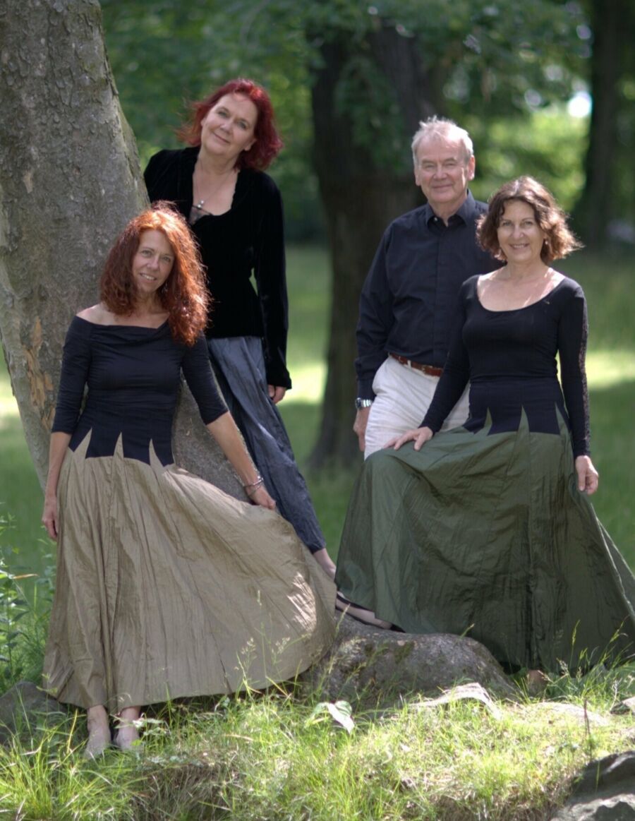 vier Musiker (3 Frauen und ein Mann) stehen im Grünen an einem Baum