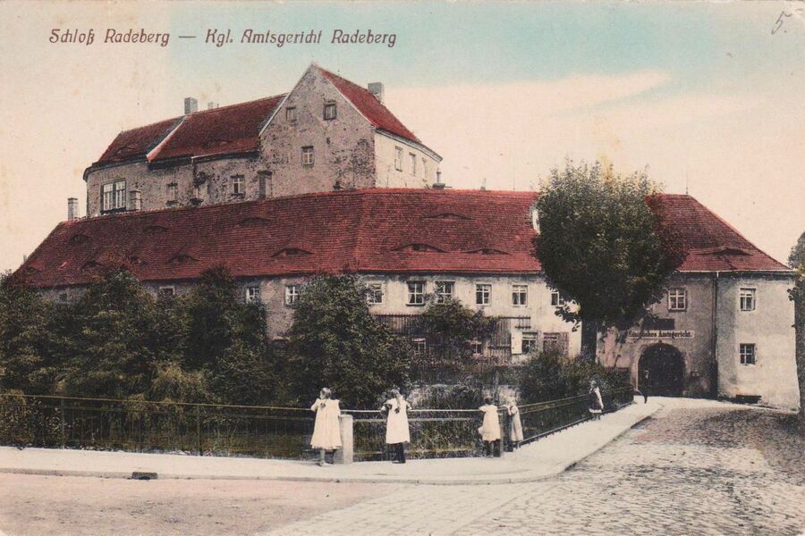 Koloriertes Schwarz-Weiß-Foto von der Vorburg mit Amtsgefängnis von 1915, Blick von der Schlossstraße zum Tor und der Vorburg, im Hintergrund die Hauptburg