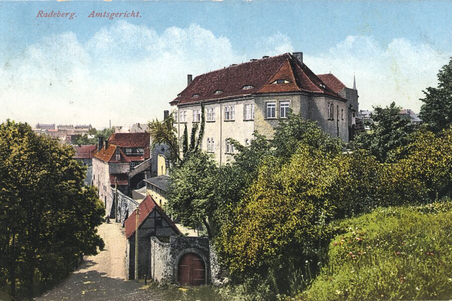 Koloriertes Schwarz-Weiß-Foto mit Blick auf das Schloss und den Weg an der Schlossmauer, im Vordergrund das Tor am Eulenturm