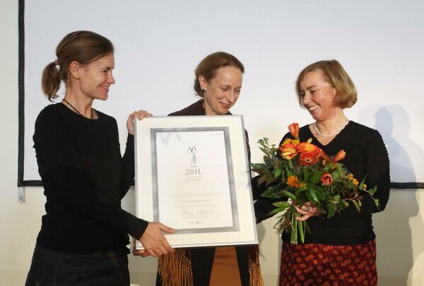 Zwei Frauen, die eine Urkunde überreichen, und eine Frau mit Blumenstrauß. In der Bildmitte steht Ministerin Freifrau von Schorlemmer, rechts Schlossleiterin Katja Altmann.