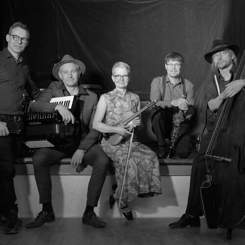 Fünf Musiker der Gruppe Klezmart sitzen und stehen vor schwarzem Hintergrund mit Akkordeon, Geige, Klarinette und Kontrabass