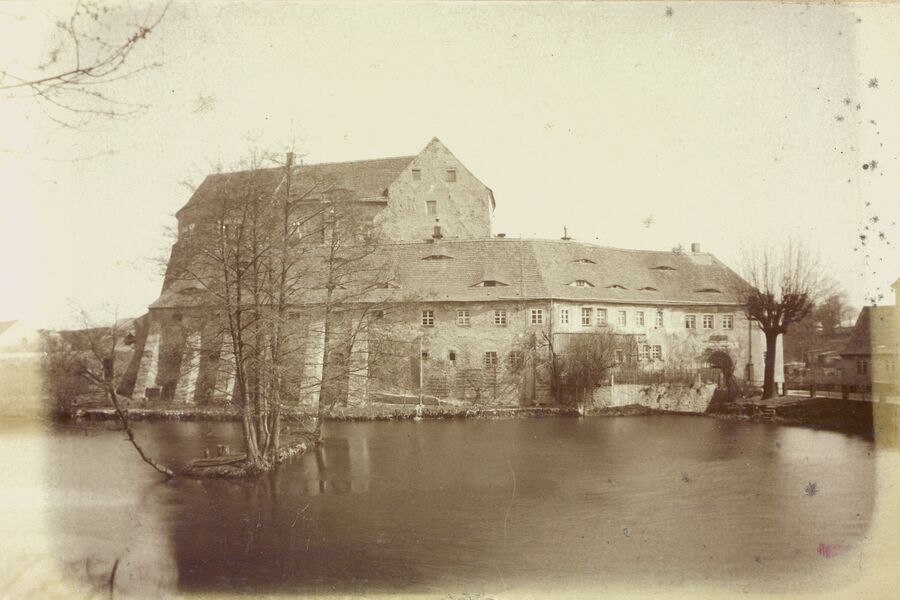 Historische Schwarz-Weiß-Fotografie mit Blick über den noch großen Schlossteich auf das gesamte Schloss