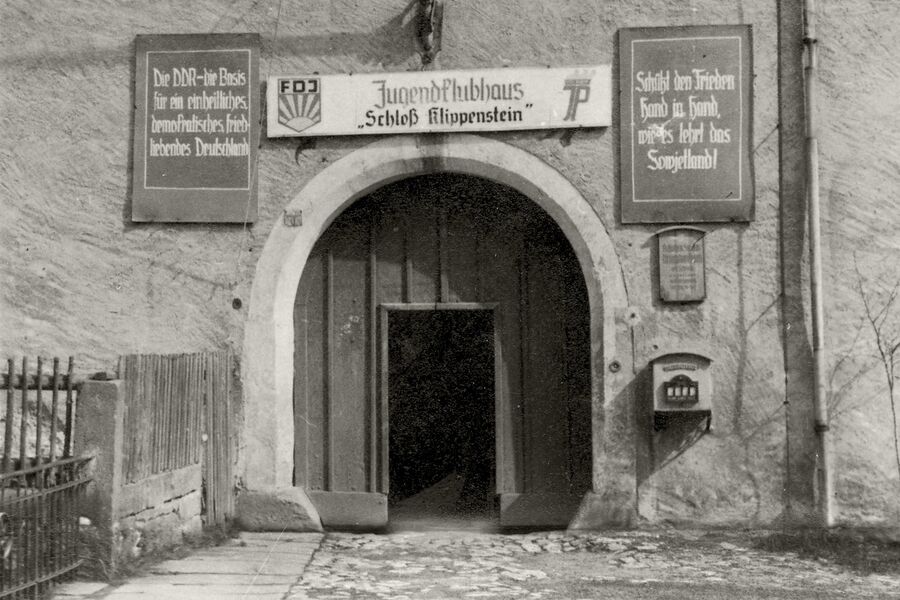 Historisches Schwarz-Weiß-Foto mit dem stadtseitigen Schlosstor und der Überschrift "FDJ-Jugendklubhaus Schloss Klippenstein" aus den 1950er Jahren